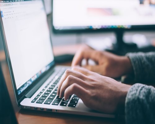 Person typing on a laptop with comfortable lighting and good posture